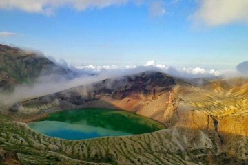 Même l'eau du lac volcanique Okama, au sommet du mont Zao, devient verte tandis que les nuages passent au dessus