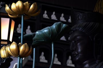 <p>Lotus flowers, lit lantern and Buddha statues in the hall</p>