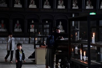 <p>A visitor was lighting a candle to offer prayers. You can see from the size of the statues in the wall shelves in the background how gigantic the Big Buddha must be.</p>