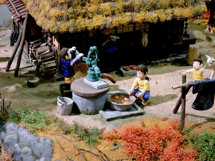 <p>A girl washes persimmons under a water pump in this model</p>