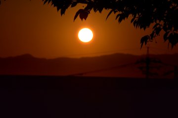 <p>The huge round-shaped sun setting over a mountain</p>