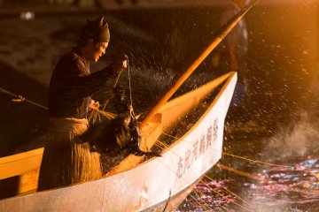<p>A cormorant sprays the fisherman with water</p>