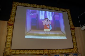 <p>A large screen playing Crayon Shin-chan episodes and promoting the most recent movie greets visitors at the entrance. A very appropriate design frames the screen.&nbsp;</p>