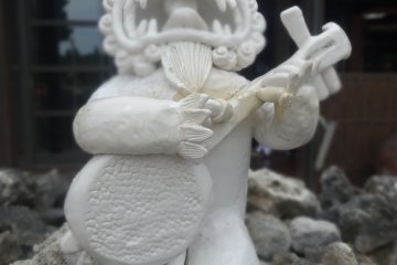 <p>This shisa is playing the sanshin, a traditional Okinawan instrument that inspired the mainland version, called the shamisen</p>