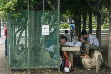 <p>Too old for the mini-themepark? These teens know how to entertain themselves, chowing down yakisoba under the shade.</p>
