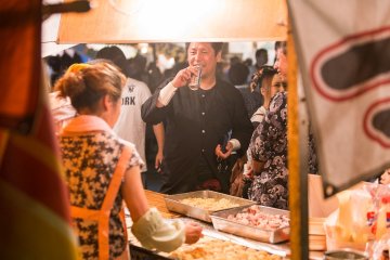 Food vendors sell various Japanese festival food, like Takoyaki (grilled dough balls stuffed with octopus)