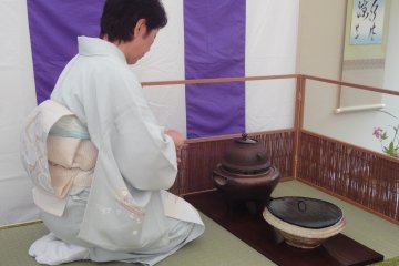 The host continues fine manners to clear the tea-serving area after the guests have left