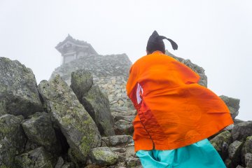 <p>A Shinto priest ascends the final steps to the summit</p>