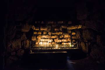 <p>Dark except for the warm glow of candlelight, hundreds of votive tablets are hung wishing for relieve from eye ailments.</p>