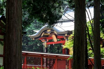 <p>Red shrine hall seen through the trees</p>