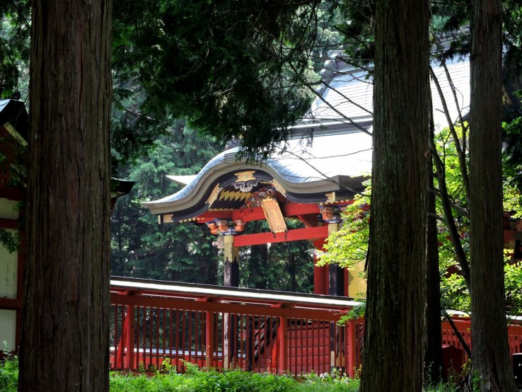 <p>Red shrine hall seen through the trees</p>