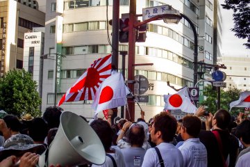 <p>A large crowd gathers at a crossing close to the exit of Kudanshita Metro Station</p>