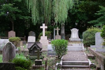 Inside the cemetery. Just behind the gravestones is a road bordering the cemetery and a lage apartment building.