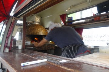 A chef cooks pizza in a real brick oven in his food truck