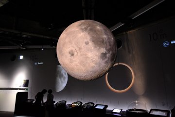 <p>A model of the moon floating in the galaxy display room with many other stars/planets</p>