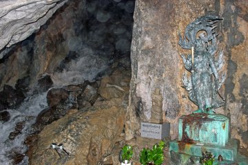 <p>The main chamber of the cave, the waterfall and a statue of Fudomyo, the Buddhist deity of discipline</p>