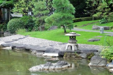 <p>A three-legged lantern sits at the edge of the pond</p>