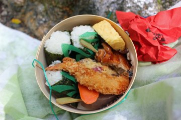 <p>The lunch&nbsp; bento, three onigiri rice balls, vegetable and shrimp tempura, chicken kushiyaki (Japanese chicken skewer), egg and konyaku</p>