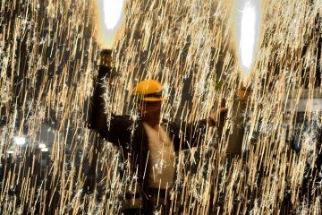 Handheld fireworks held in the man's hand shower sparks down around him.
