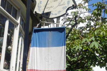 <p>A French tricolor hangs beneath the sign for the restaurant</p>