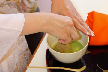 <p>The bamboo tea whisk and back and forth movement of her hand makes the tea frothy</p>