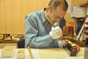<p>A crafstmen works with metal that's used to decorate the Buddhist altars</p>