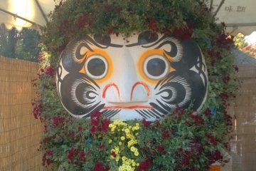 A Daruma doll decorated with leaves and flowers