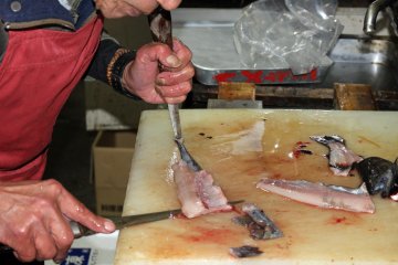 <p>Pemilik toko menguliti dan mengiris ikan yang baru ditangkap</p>