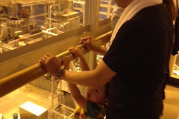 My son and husband gaze through a window overlooking the beer production machinery.