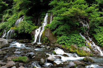 Multiple threads flow down the hillside into the river