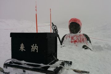 A Jizo statue buried up to its chest in the snowfall. Return during summer to see it in full