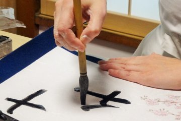 The host writes a guest's name in kanji