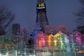 Patung es yang indah diterangi dengan Sapporo TV Tower di belakangnya