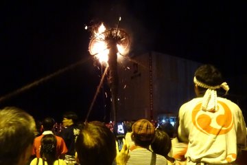 Locals and visitors watch a taimatsu burn down; who will catch the gohei this year?