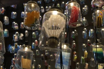 Memory Bottle by Mayumi Kuri features a very large collection of jars suspended from the ceiling, each filled with a memory from an island resident.