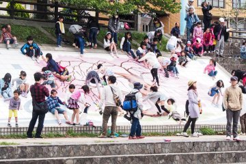 Kids sliding down the side of the river bank.