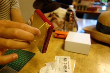 A workshop participant cautiously peels the masking tape off her design
