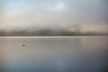 The first rays of light illuminate the fringe of clouds over the lake