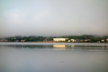 Sunlight touches Lake Yamanakako, seemingly bringing it to life as cars zip along the roads and shopfronts begin to open