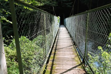 Narrow suspension bridge over a river crossed by the trail