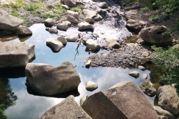 Gray stones contrast the blue reflected in the water