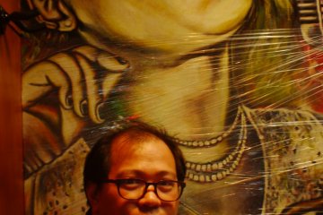 At a bar, a friend poses before a screaming wall