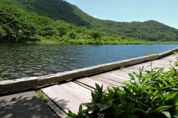 A wooden walk-way extends along one side of the lake