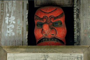 A tengu face glares with yellow eyes