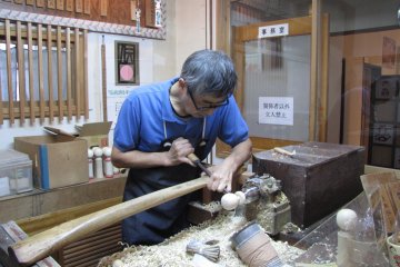 A craft worker transforms a block of wood in to doll