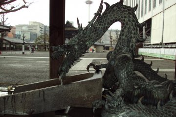 Purify your hands with water from the dragon. Notice Kyoto Tower in the background.