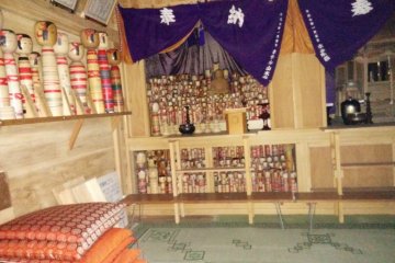 A camera flash reveals sleeping kokeshi
