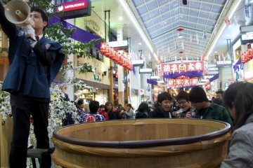 A huge wooden barrel collects offerings in front of the shrine.