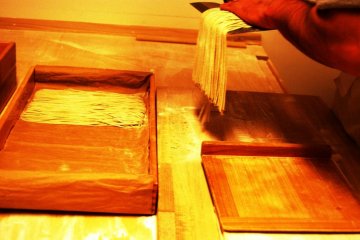 Transfering each knife-full of soba in orderly fashion into a wooden box