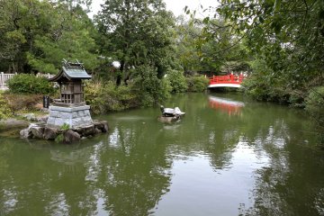 Pond with red bridge, stone turtle and small island shrine